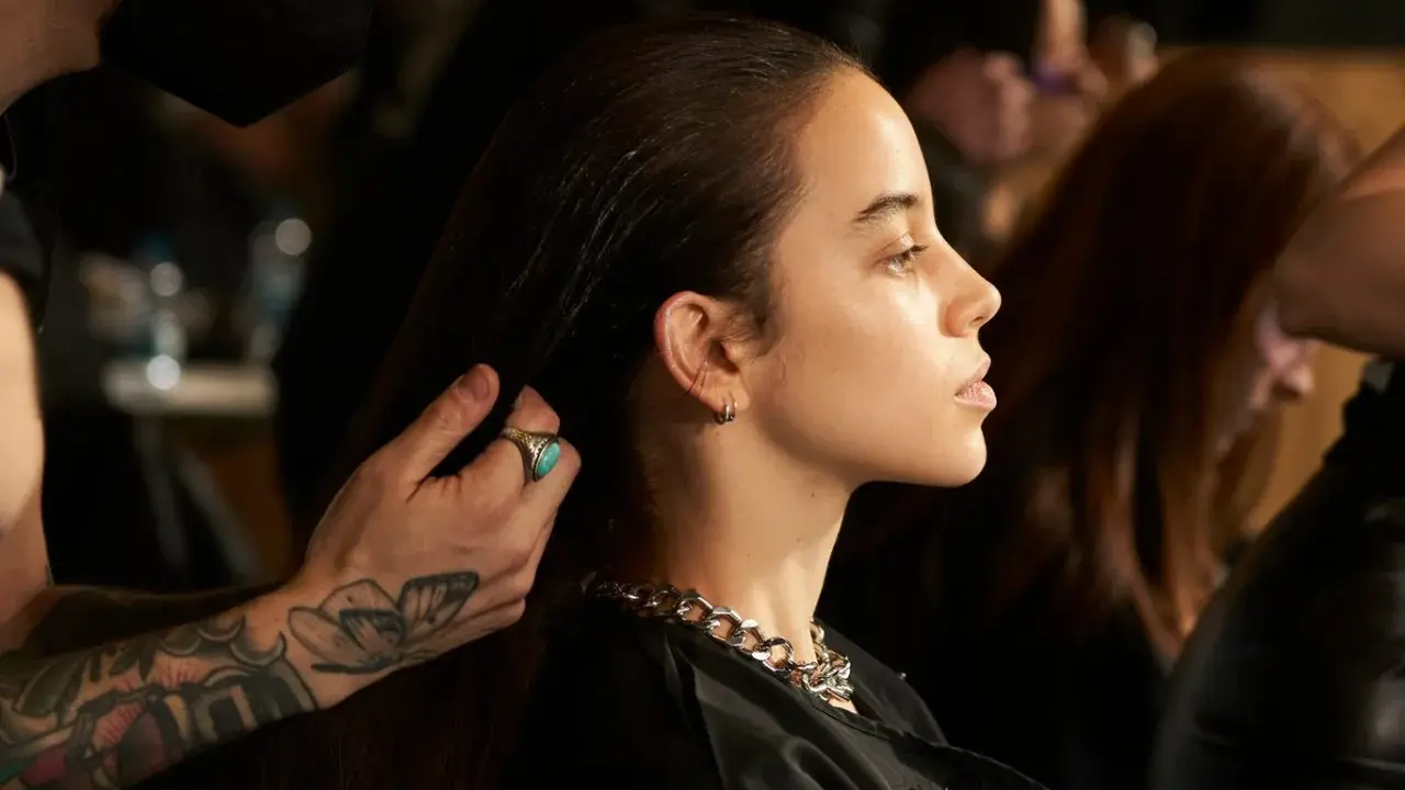 Stylista układa włosy modelki, ukazując olśniewające olaplex efekty: jedwabistość i blask.