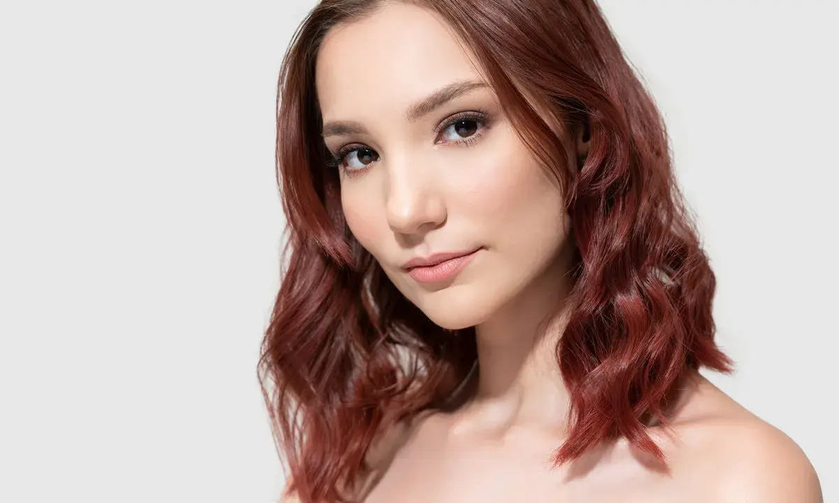 Mahoń kolor włosów komu pasuje? Modelka z rudymi, falowanymi włosami prezentuje ten odcień.