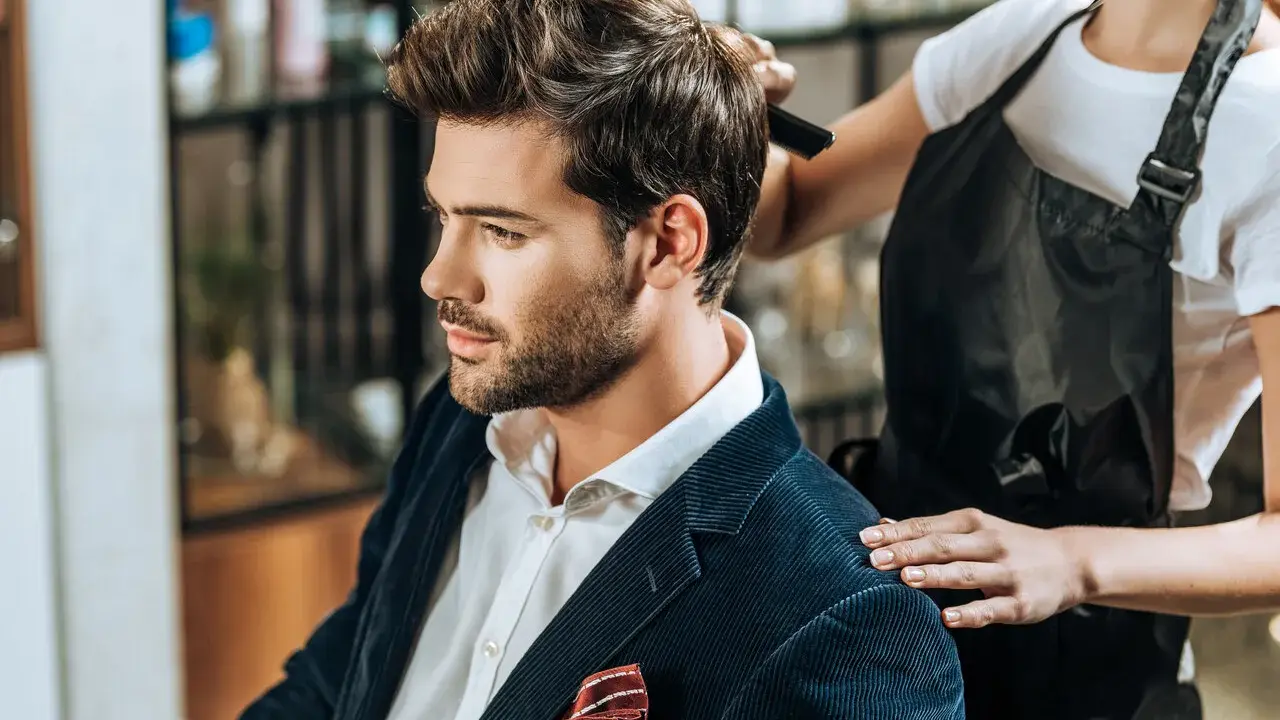 Elegancka fryzura męska w trakcie stylizacji. Mężczyzna w garniturze z pewnością doceni profesjonalizm.