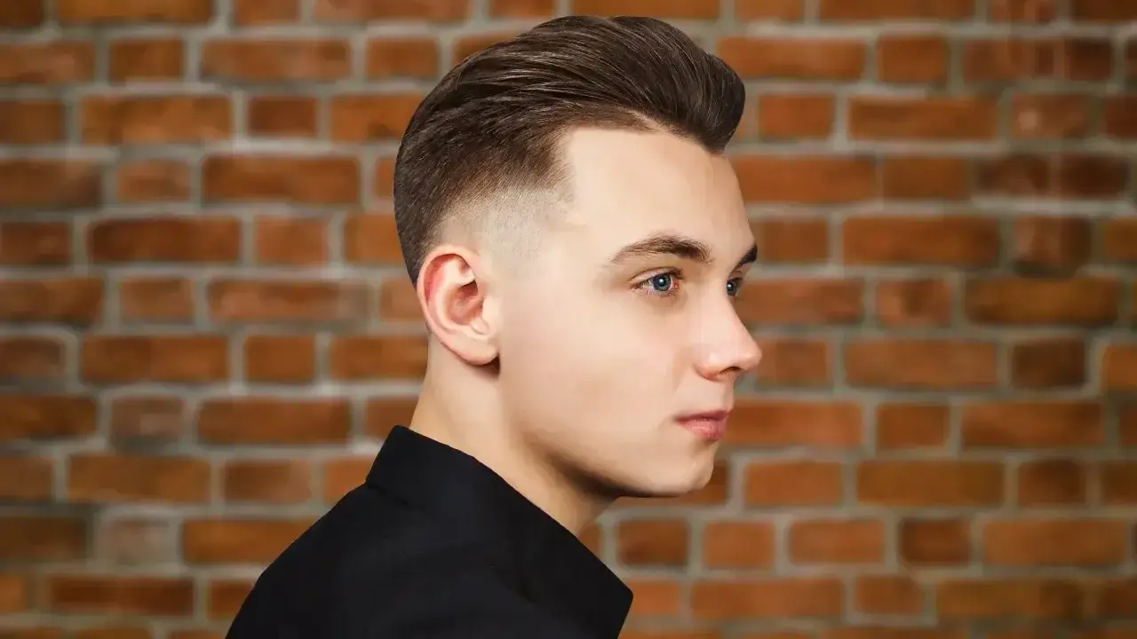 Młody mężczyzna z modną fryzurą, która dodaje mu uroku. To jedne z tych fryzur męskich, które odmładzają i podkreślają rysy twarzy.