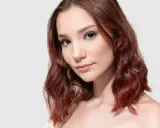 Mahoń kolor włosów komu pasuje? Modelka z rudymi, falowanymi włosami prezentuje ten odcień.