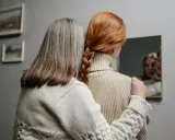 Dwie kobiety, jedna z rudymi włosami splecionymi w warkocz, druga z siwymi, patrzą w lustro. Czy toner pokryje siwe włosy?
