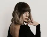 Kobieta z ciemnymi, falowanymi włosami w stylu prosty bob fryzura, z grzywką i ombre.