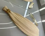 Pytasz, ile kosztuje przedłużanie włosów? Na zdjęciu widać pasma blond włosów gotowe do przedłużenia, obok złote grzebienie.