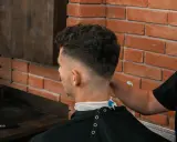 Chłopak z puszystymi włosami w salonie fryzjerskim, z modnym cieniowaniem.