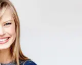Uśmiechnięta blondynka z niebieskimi oczami i idealnie ułożoną grzywką. Dowiedz się, jak obciąć grzywkę żeby się dobrze układała.