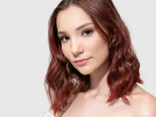 Mahoń kolor włosów komu pasuje? Modelka z rudymi, falowanymi włosami prezentuje ten odcień.