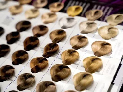 Próbki włosów prezentują szeroką gamę odcieni, od ciemnego brązu po jasny blond. Różnorodne poziomy kolorów włosów tworzą paletę możliwości.