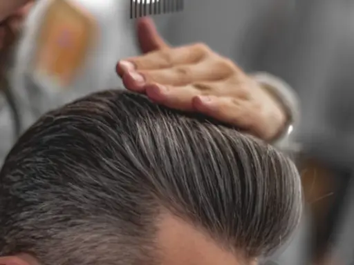 Stylista układa włosy, pokazując, jak mieć gęste włosy chłopak.