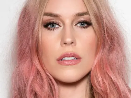 Kobieta z truskawkowym blond kolorem włosów, błękitnymi oczami i delikatnym makijażem.