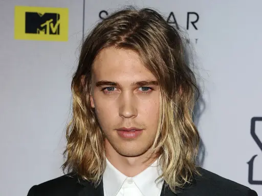 Austin Butler z długimi, falowanymi włosami, który udowadnia, komu pasują długie włosy męskie.