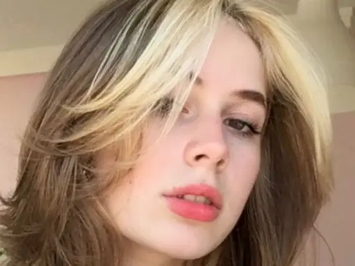 Dziewczyna z burzą blond i brązowych włosów w stylu curly wolf cut, z pasemkami przy twarzy.