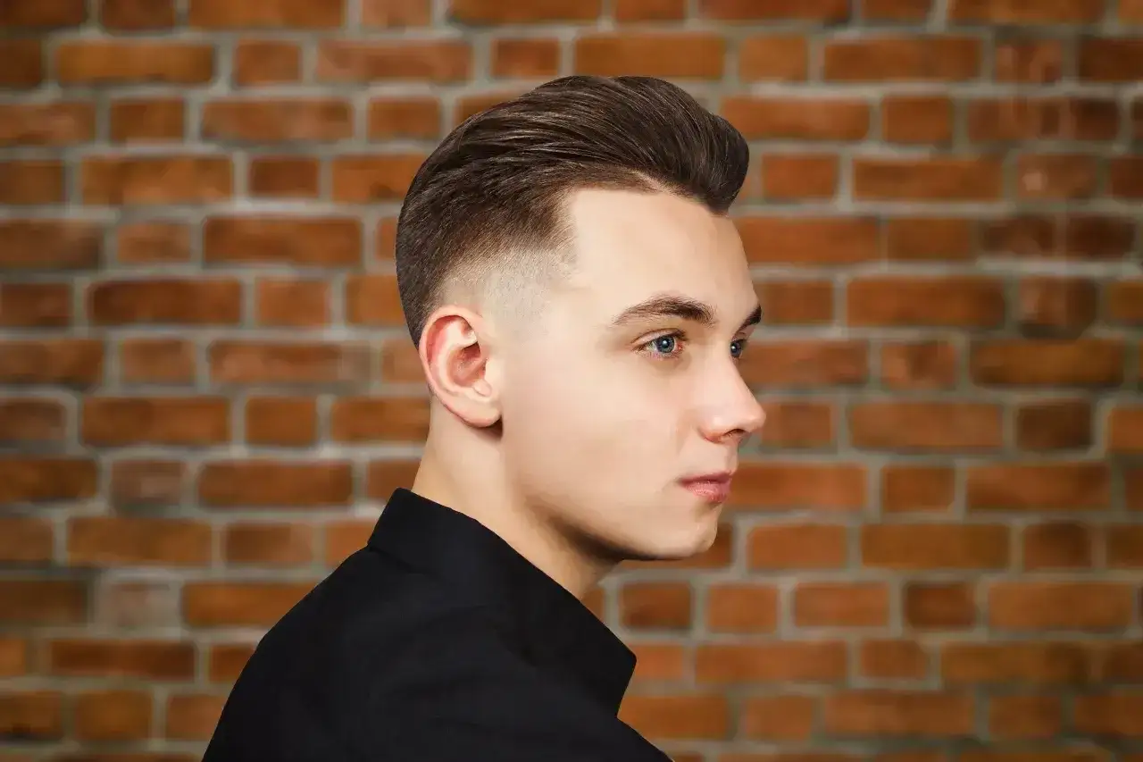 Młody mężczyzna z modną fryzurą, która dodaje mu uroku. To jedne z tych fryzur męskich, które odmładzają i podkreślają rysy twarzy.