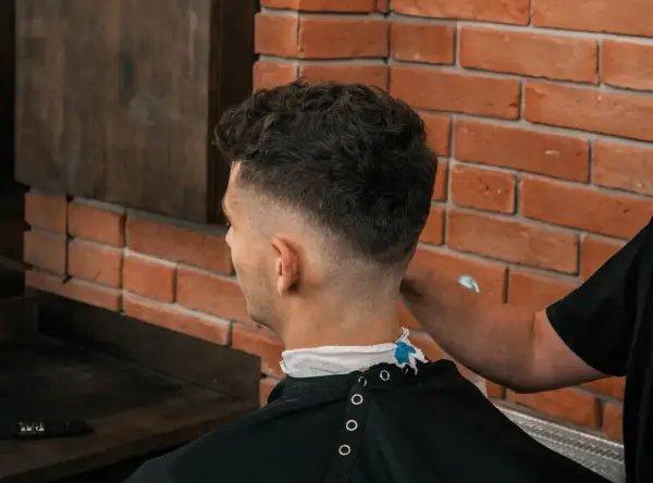 Chłopak z puszystymi włosami w salonie fryzjerskim, z modnym cieniowaniem.